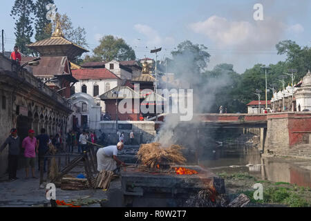 Al Tempio di Pashupatinath vicino al fiume Bagmati a Kathmandu, Nepal, un uomo dalla casta Dom 'intoccabile' conduce una cremazione indù Foto Stock