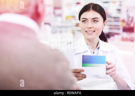 Sorridente giovane dai capelli scuri il farmacista in bianco uniforme Foto Stock