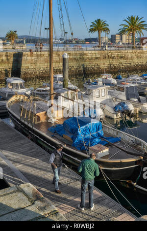 Due uomini in cerca di una barca a vela ormeggiata nel porto turistico di Ferrol, La Coruña, Galizia, Spagna, Europa Foto Stock