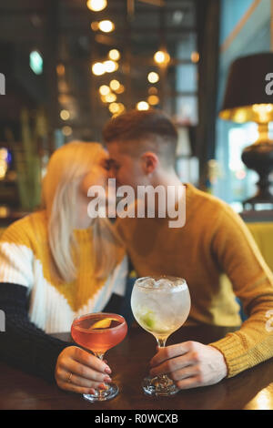 Giovane baciare e azienda bicchiere da cocktail Foto Stock