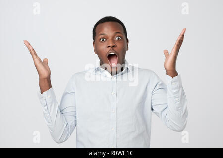 Ritratto di giovane africano uomo bello sorpreso con news ha ottenuto. Foto Stock