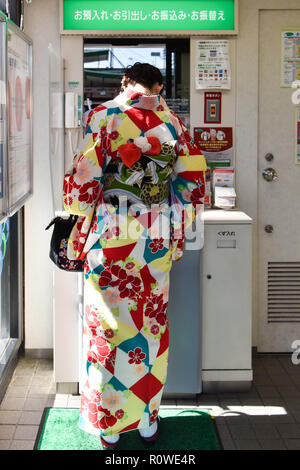 Donna Giapponese in un kimono con automatic teller, Kyoto, Giappone Foto Stock