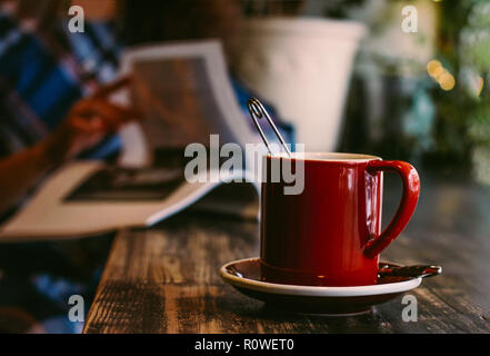 Foto atmosferica con red mug sul tavolo di legno in cafe sul ba Foto Stock