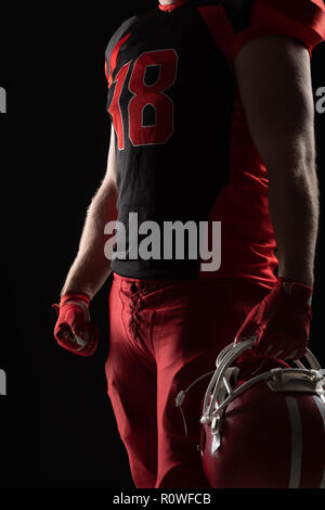 Giocatore di football americano in piedi con casco su sfondo nero Foto Stock