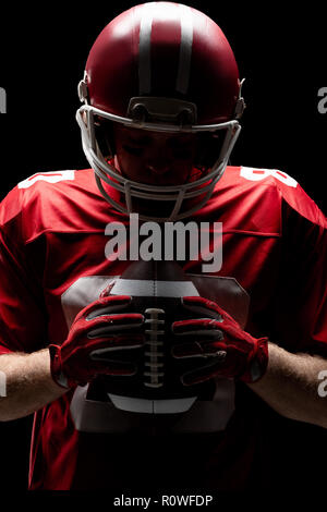 Giocatore di football americano con helmat guardando il pallone da rugby Foto Stock