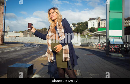 Donna incinta sventolando presso la fermata degli autobus Foto Stock