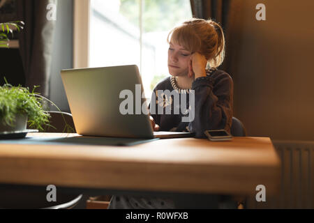 Donna che utilizza portatile a casa Foto Stock