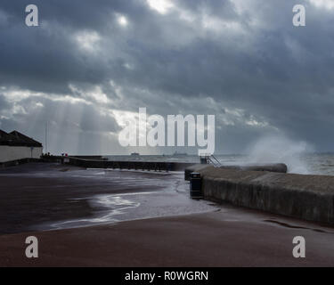 Onde che si infrangono sul mare difese a Southsea beach con i raggi di luce provenienti attraverso le nuvole Foto Stock