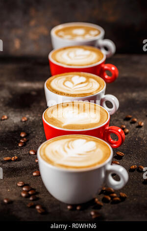 Molte tazze di cappuccino con latte art su sfondo scuro Foto Stock