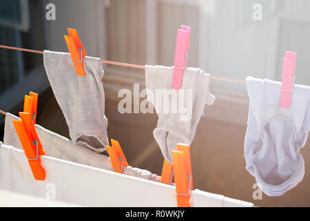 Calzini bagnati essiccamento appeso su una linea di abbigliamento con clothespins in una giornata di sole Foto Stock