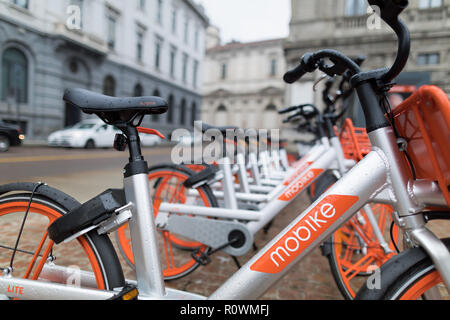 Milano, Italia - 27 Ottobre 2018: Piazza della Scala, noleggio di biciclette parcheggiate in una fila sulla piazza. L'arancio e silver le biciclette sono da Mobike, un com Foto Stock