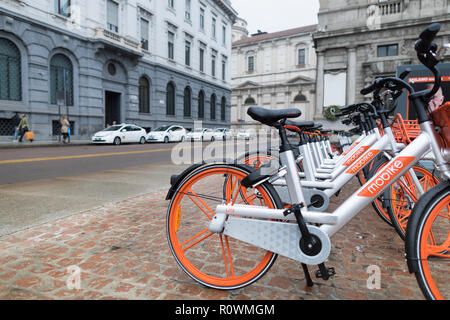 Milano, Italia - 27 Ottobre 2018: Piazza della Scala, noleggio di biciclette parcheggiate in una fila sulla piazza. L'arancio e silver le biciclette sono da Mobike, un com Foto Stock