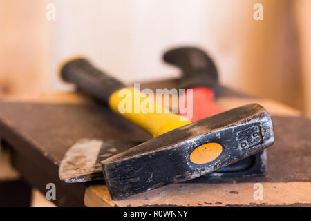 La creazione di strumenti. Lavori in legno. Martello di colore giallo e rosso ax su legno scuro dello sfondo. Close up Foto Stock