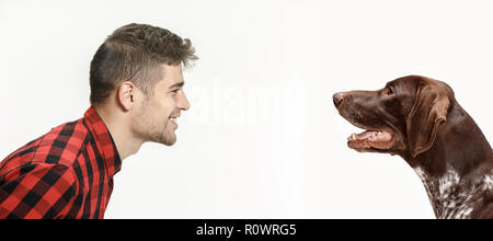 Ritratto emotivo dell uomo e il suo cane, il concetto di amicizia e la cura dell'uomo e l'animale. Il tedesco Shorthaired puntatore - Kurzhaar cucciolo di cane isolato su bianco di sfondo per studio Foto Stock