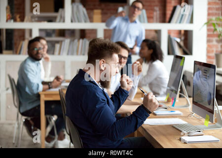 Maschio eccitato dipendente sente euforici raggiungimento obiettivo finanziario Foto Stock