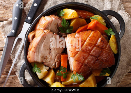 Krustenbraten arrosto di maiale con cotenna croccante con verdure close-up in una padella sul tavolo. parte superiore orizzontale vista da sopra Foto Stock