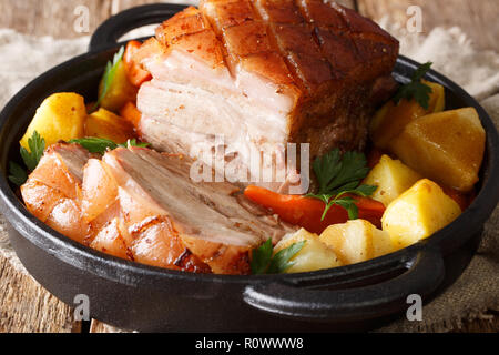 Tedesco krustenbraten di maiale cotto nella birra con verdure e salsa di close-up in una padella sul tavolo. orizzontale. Foto Stock