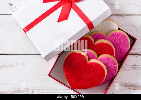 A forma di cuore i cookie in confezione regalo per il giorno di San Valentino su bianco tavolo in legno. Vista superiore Foto Stock