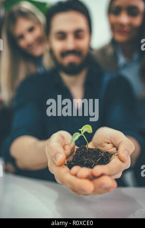 Università collega biologi è in possesso di una giovane pianta nel suolo in mani e controllare la qualità del campione. Foto Stock