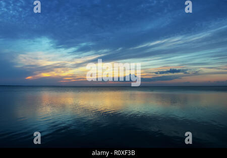 Quasi il tramonto South Padre - Molto blu nubi con il tramonto del sole che appare all'orizzonte tutto si riflette nell'oceano Foto Stock