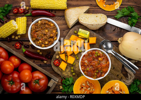 Due Winter Warmer stufati circondato da ingredienti overhead shot: zucca stufato e chili con carne Foto Stock