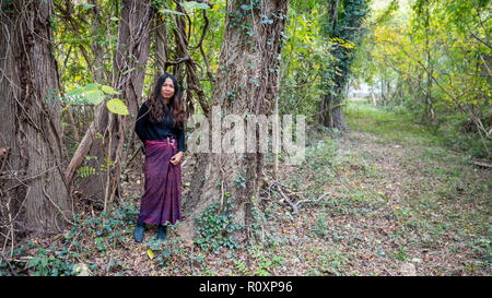 Donna Thai in piedi nella foresta accanto agli alberi di sarong Foto Stock