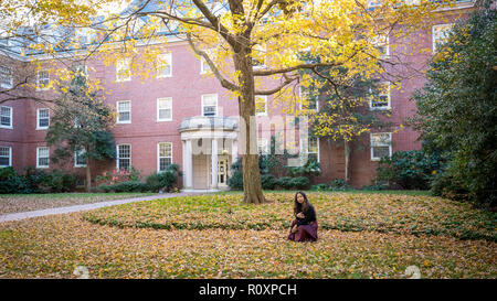 Donna Thai in ginocchio di fronte a palazzo universitario in autunno Foto Stock