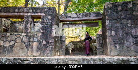 La donna in piedi di uscio di anfiteatro in pietra in sarong Foto Stock