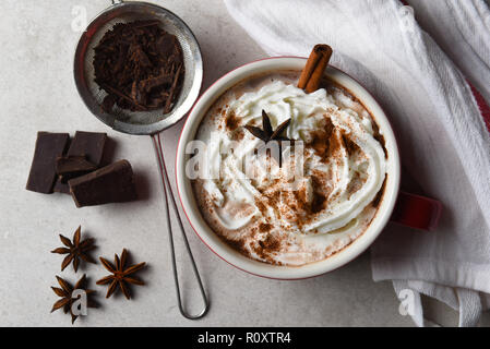 Vista dall'alto di una grande tazza di cioccolata calda la torta con panna montata e cannella e anice stellato. Foto Stock