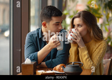 Giovane coppia attraente su data nel coffee shop avente una conversazione e godendo del tempo trascorso con ogni altro. Foto Stock