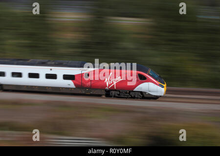 Un Virgin Trains classe 390 Pendolino ad alta velocità brandeggio treno treno ruotato ad una velocità rapida sulla linea principale della costa occidentale a Harthorpe, Scozia Foto Stock