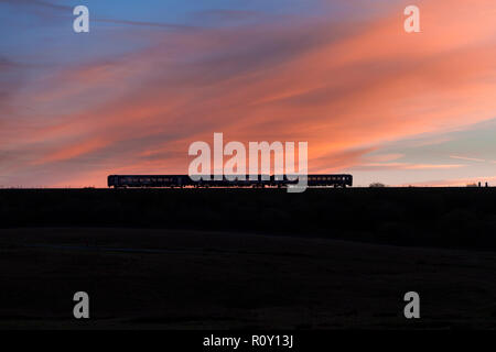 Arriva Nord classe rampa 153 + 158 sprinter treni a Ribblehead sull'accontentarsi di Carlisle linea ferroviaria al tramonto Foto Stock