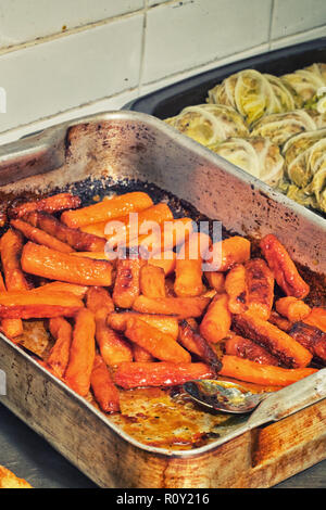 Le carote arancione rivestito in miele sono cotti e seduti in un vassoio pronte per essere servite su un piatto. Foto Stock