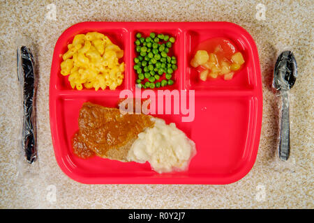 Scuola elementare il pranzo salisbury steak sul vassoio con piselli maccheroni e formaggio e salsa di mele Foto Stock