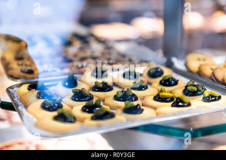 Frollini stile italiano dei cookies sul display di vendita al dettaglio in negozio, negozio, panetteria attraverso finestra, con tutto il pistacchio e caramello nero sulla parte superiore del vassoio Foto Stock