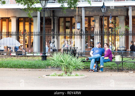 New Orleans, Stati Uniti d'America - 22 Aprile 2018: il centro città vecchia Louisiana town city con il famoso Jackson Square park, coppia romantica gente seduta sul banco il resto Foto Stock