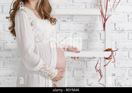 Giovane donna incinta in piedi rivolta lateralmente Foto Stock