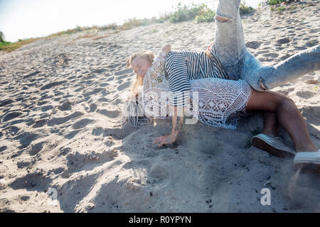 Donna con il bianco dreadlocks abbracciando il suo bel ragazzo disteso sulla sabbia Foto Stock