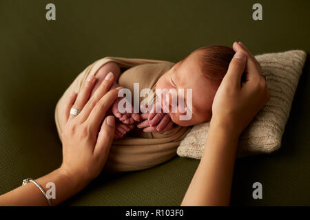 Da sopra il colpo di mano della madre anonimo toccando delicatamente sleeping neonato Foto Stock