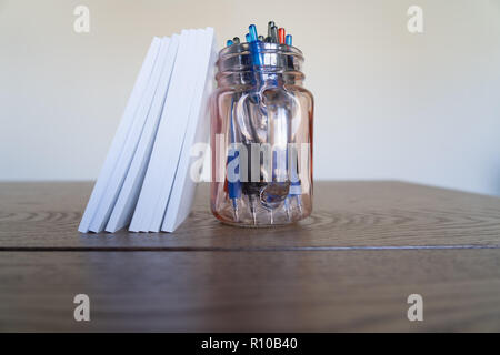 Blocchi di appunti con un vaso di penne come un bookend Foto Stock