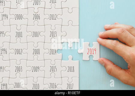 Mano aggiunge una parte mancante al puzzle con testo 2019 Foto Stock