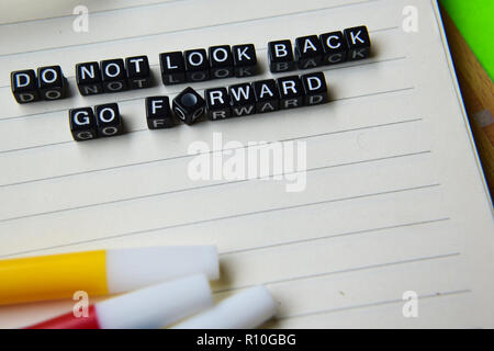 Non guardare indietro andare avanti il messaggio scritto su blocchi di legno. Istruzione e motivazione concetti. Croce immagine elaborata su sfondo verde Foto Stock