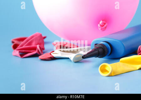 Pompa pneumatica il gonfiaggio di un palloncino rosa su sfondo blu Foto Stock