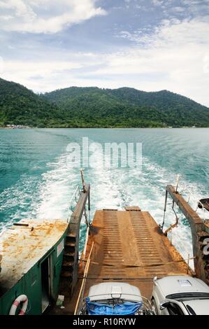 Rampa di traghetto e tracciare sull'acqua di mare tropicale dietro il traghetto, con Koh tropicale Isola Chang sull orizzonte in Thailandia Foto Stock