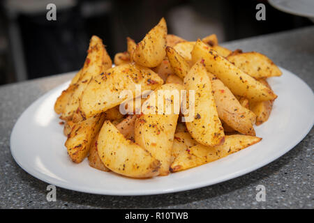 Una ciotola di Spicchi di patate , patate arrosto cunei Foto Stock