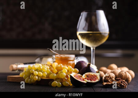 Succosa fresco intero di fig frutti e un taglio di fichi e ciotola di miele in favi sul tagliere di legno Foto Stock