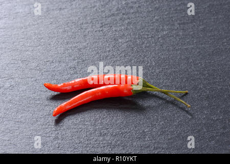 Due red hot chili peppers su sfondo nero Foto Stock