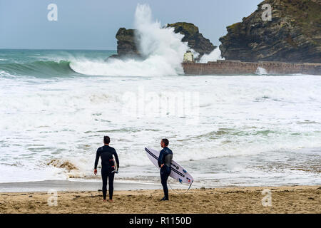 Surfers stand parlando come onde giganti pastella il porto di pareti e scogliera bordi. Foto Stock