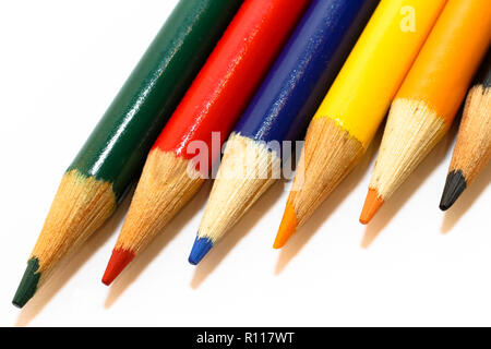 Matite colorate in colori verde, rosso, blu, giallo, arancio e nero, allineati fianco a fianco in un primo piano foto macro isolato su un bianco senza giunture bac Foto Stock
