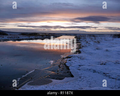 Vista del fiume congelato e la terra al tramonto a dicembre in Islanda Foto Stock